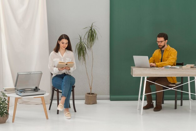 Donna che si distende durante la lettura di libri e uomo che lavora al computer portatile