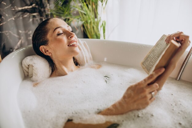 Donna che si distende nella vasca da bagno con le bolle