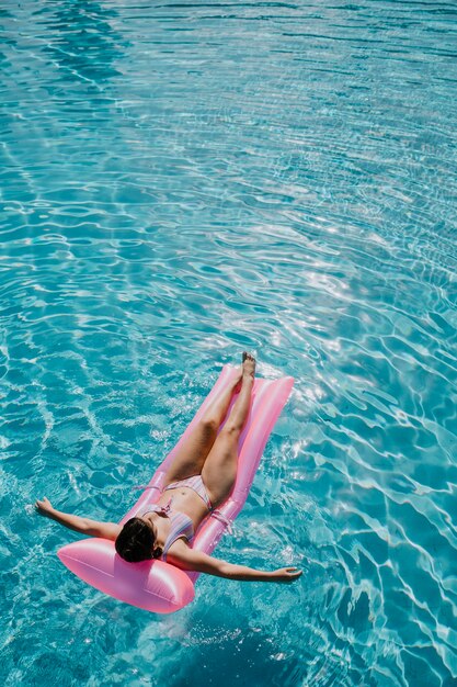 Donna che si distende sul materasso in piscina