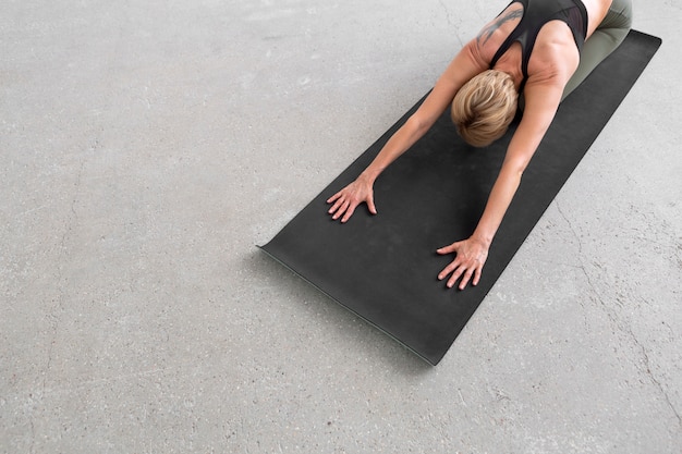 Donna che si estende sulla stuoia di yoga