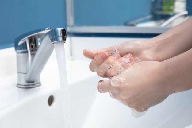 Donna che si lava accuratamente le mani con sapone e disinfettante, primo piano.