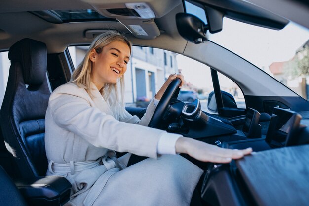 Donna che si siede all'interno dell'elettro automobile mentre si carica