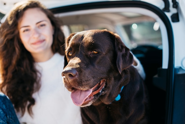 Donna che si siede con il suo cane nel bagagliaio aperto