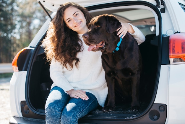 Donna che si siede con il suo cane nel bagagliaio aperto