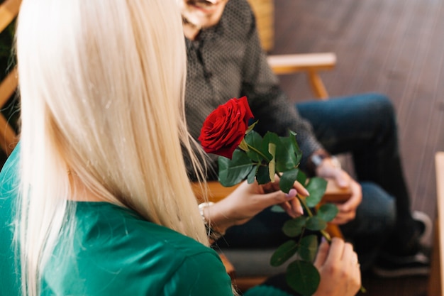 Donna che si siede con il suo ragazzo che tiene bella rosa rossa