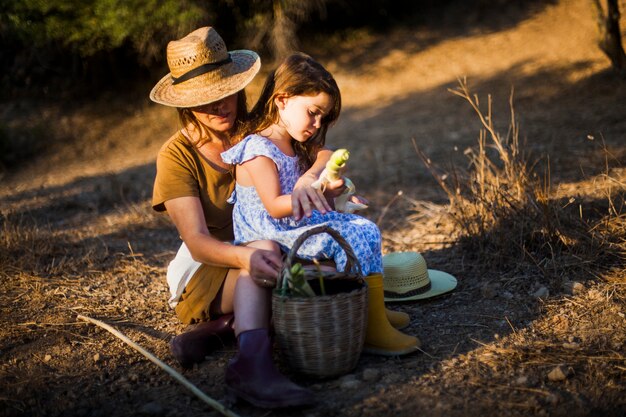 Donna che si siede con sua figlia nel campo