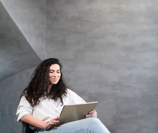 Donna che si siede e che esamina il computer portatile