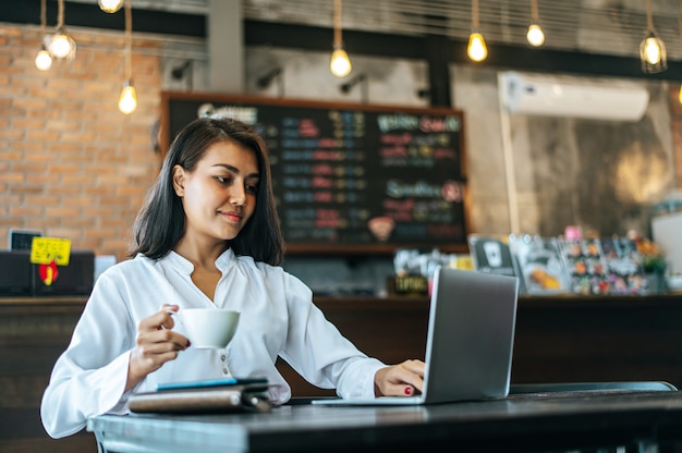 donna che si siede e che lavora con un computer portatile in una caffetteria