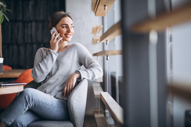 Donna che si siede in un caffè bevendo caffè e lavorando su un computer