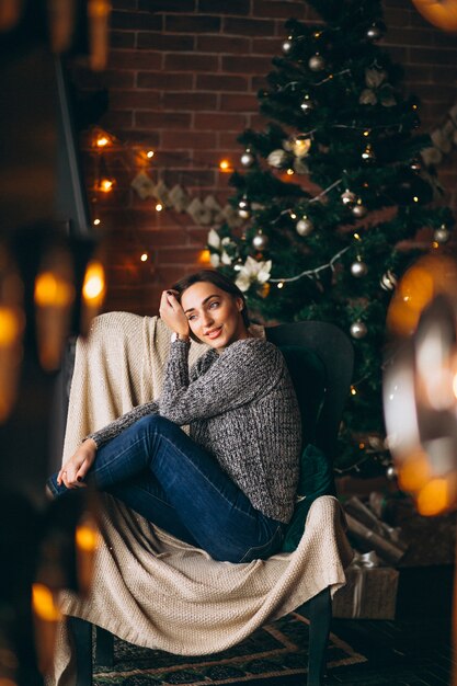 Donna che si siede nella sedia dall&#39;albero di Natale