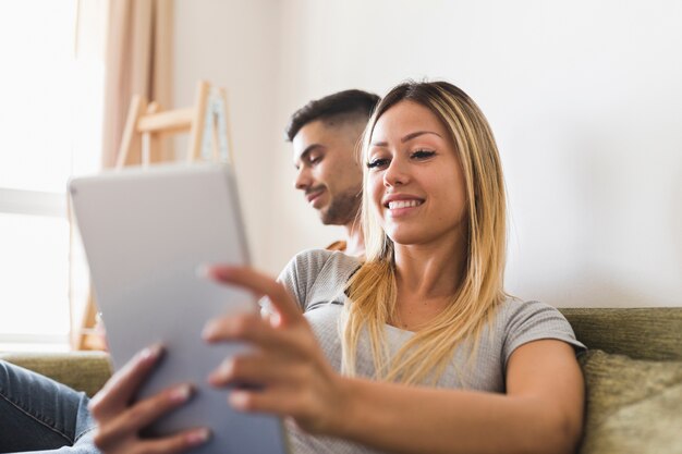 Donna che si siede sul divano utilizzando la tavoletta digitale