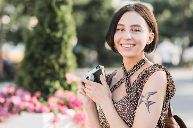 Donna che sorride con la macchina fotografica all&#39;aperto