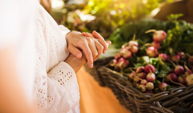 Donna che sta davanti alla stalla di verdure nel mercato