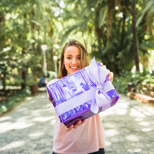 Donna che tiene il contenitore di regalo viola nel parco