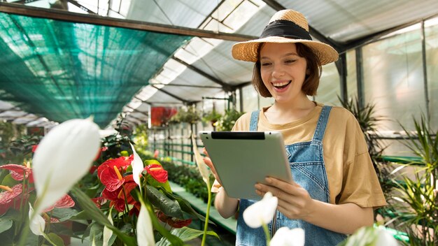 Donna che tiene il suo tablet in una serra