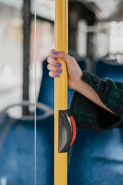 Donna che tiene la sua mano sul palo dell'autobus