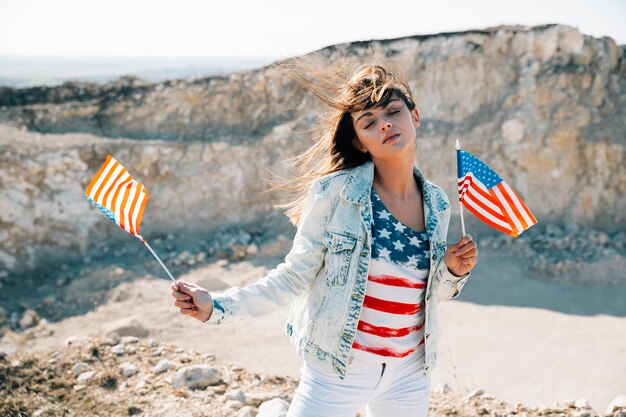 Donna che tiene le bandiere americane con gli occhi chiusi