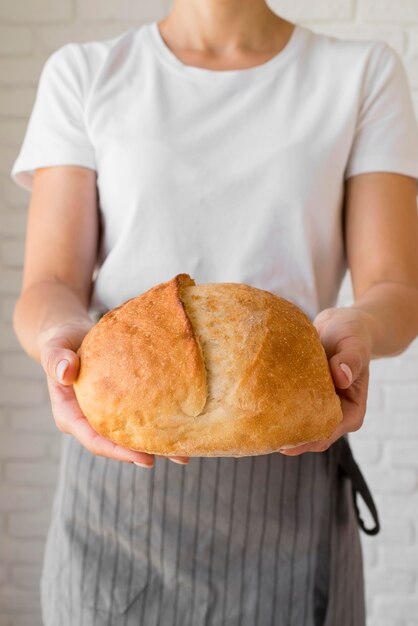 Donna che tiene pane rotondo fresco