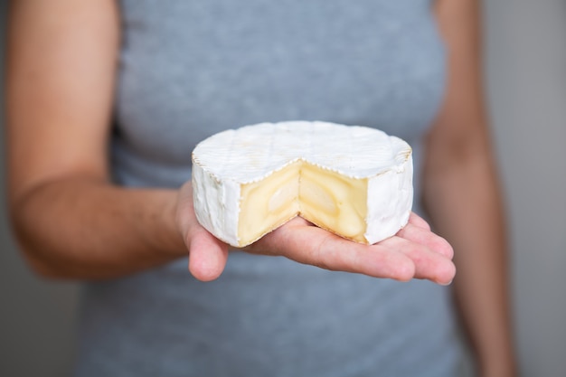 Donna che tiene pezzo di formaggio a pasta molle sulla palma