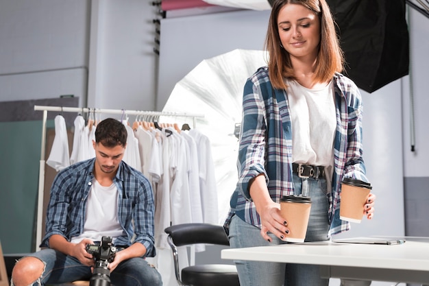 Donna che tiene tazze di caffè accanto al fotografo