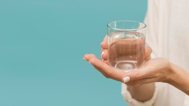 Donna che tiene un bicchiere riempito di spazio copia acqua