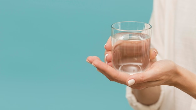 Donna che tiene un bicchiere riempito di spazio copia acqua