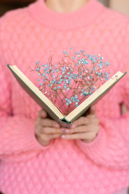 Donna che tiene un libro aperto con un mazzo di fiori secchi all'interno