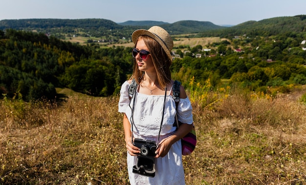 Donna che tiene una macchina fotografica e distogliere lo sguardo