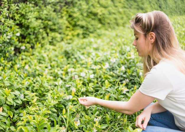 Donna che tocca i fiori nel parco