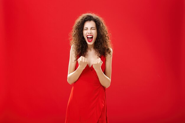 Donna che trionfa e applaude gioiosamente alzando i pugni vicino al petto urlando di felicità e gioia vicino...