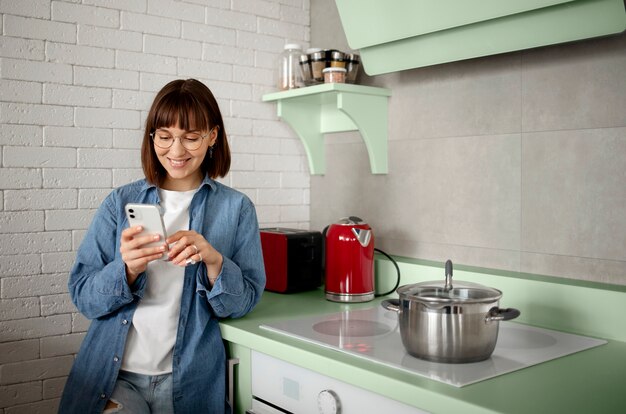 Donna che usa lo smartphone in una cucina verde
