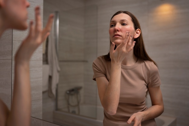 Donna che usa una crema idratante per aiutare con la condizione della pelle rosacea