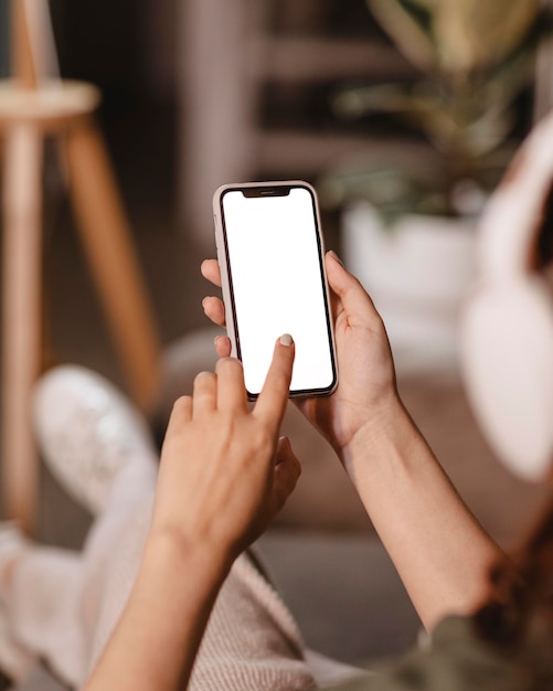 Donna che usa uno smartphone moderno e cuffie a casa
