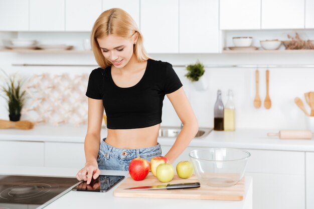 Donna che utilizza il computer della compressa nella cucina