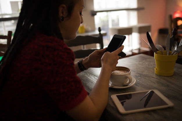 Donna che utilizza il telefono cellulare nella caffetteria