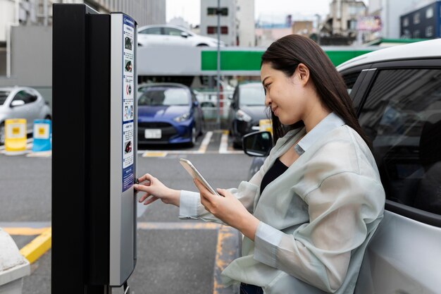 Donna che utilizza la stazione di ricarica per auto elettriche