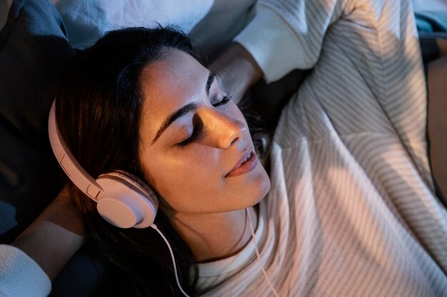 Donna che utilizza le cuffie per la musica a casa a letto