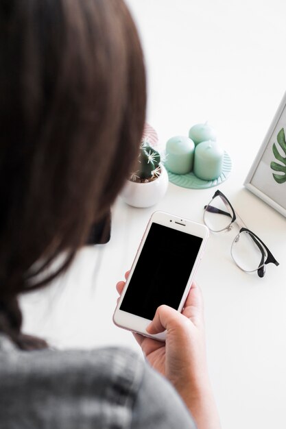 Donna che utilizza smartphone al tavolo con occhiali e candele