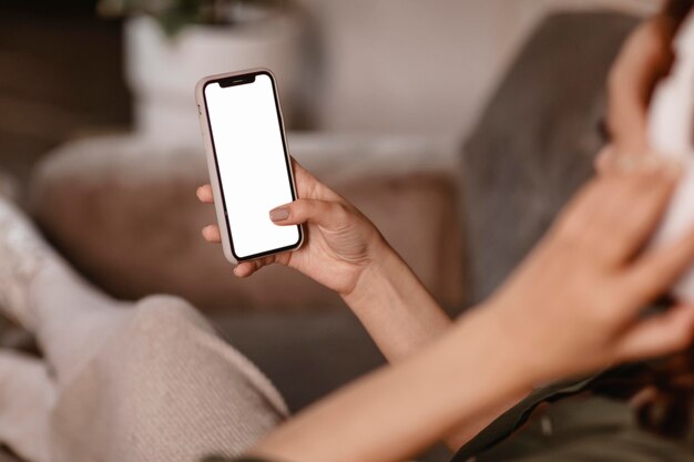 Donna che utilizza smartphone e cuffie moderne sul divano di casa