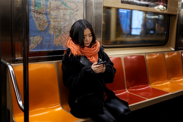 Donna che utilizza smartphone mentre viaggia sulla metropolitana della città