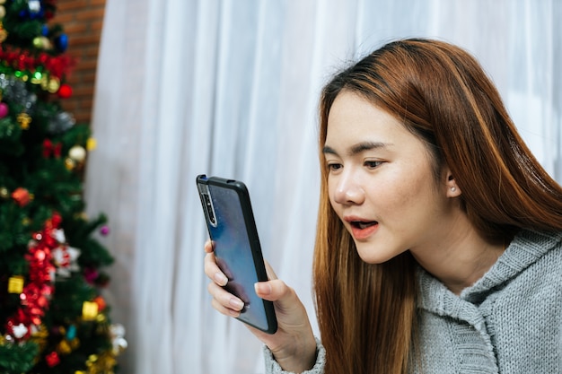 Donna che utilizza smartphone sul suo letto in una giornata fredda