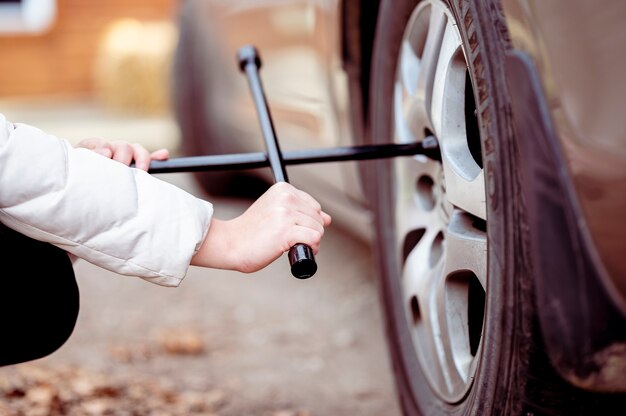 donna che utilizza uno strumento su una ruota di automobile