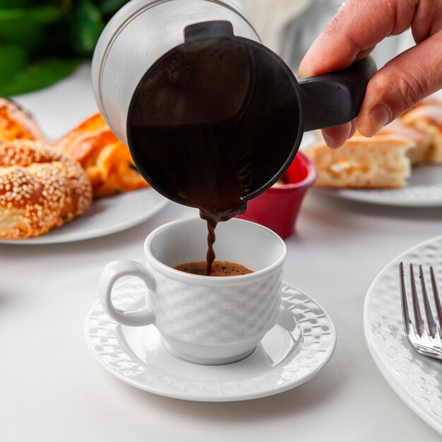 Donna che versa caffè turco nella vista laterale della tazza di caffè