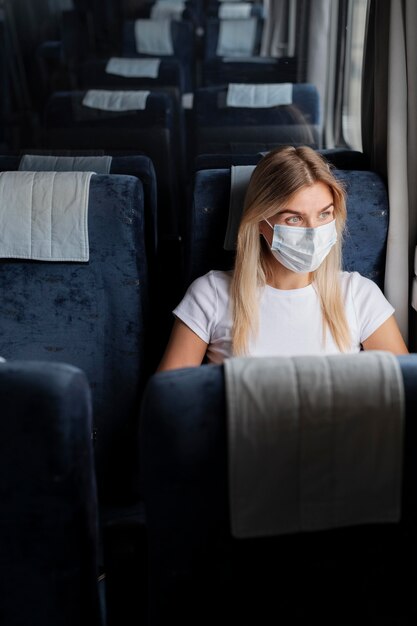 Donna che viaggia in treno indossando una maschera medica per protezione