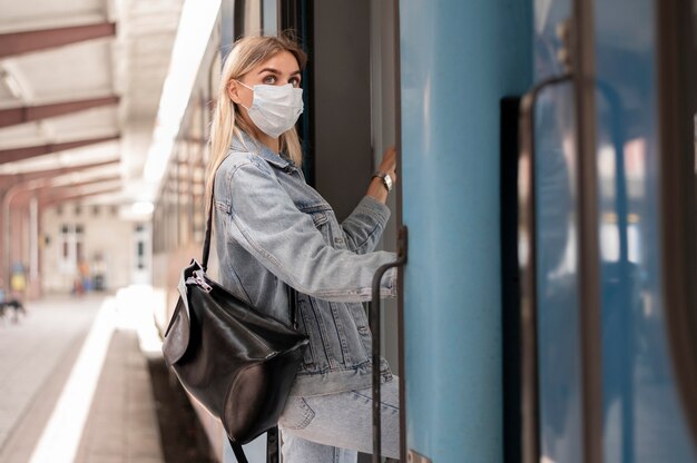 Donna che viaggia in treno indossando una maschera medica per protezione