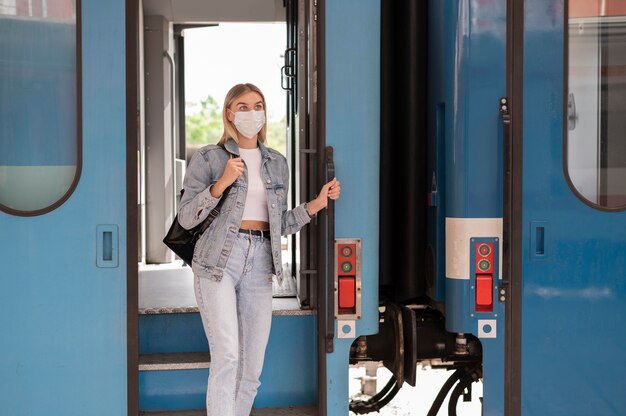Donna che viaggia in treno indossando una maschera medica per protezione