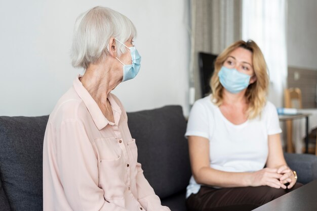 Donna che visita il suo parente a casa di cura e indossa una maschera medica