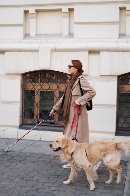 Donna cieca sorridente del colpo pieno con il cane di servizio