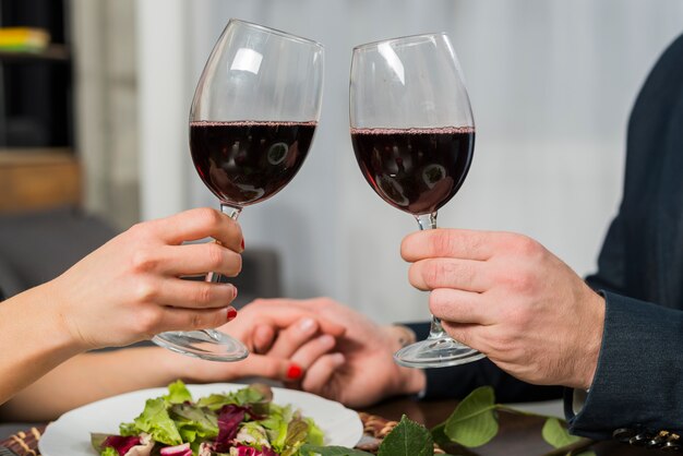 Donna clanging bicchieri di vino con l&#39;uomo al tavolo con piastra