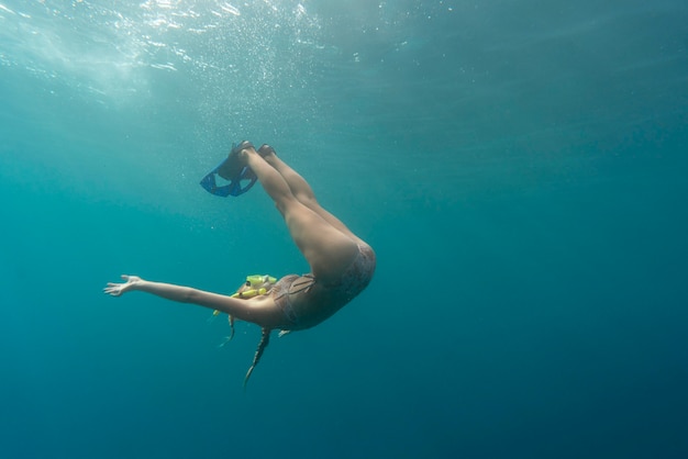 Donna con attrezzatura subacquea nuotare nell'oceano